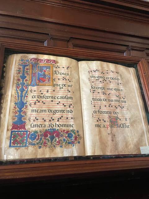 Open music book with decorated pages in a display case.