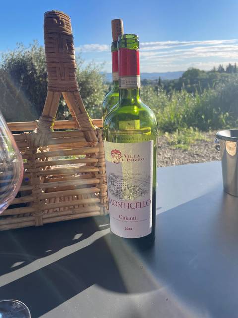 Wine bottle in a basket on a table outdoors with scenic background.