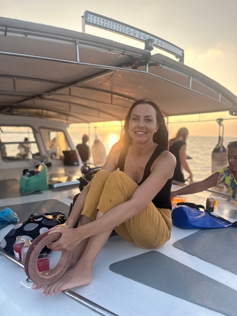 Woman sitting on a boat during sunset.