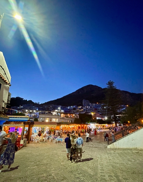       Cityscape at night with lights and shadow of a mountain.
  