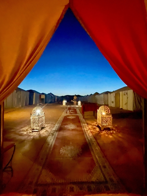       Desert camp with traditional tents and lanterns at dusk.
  