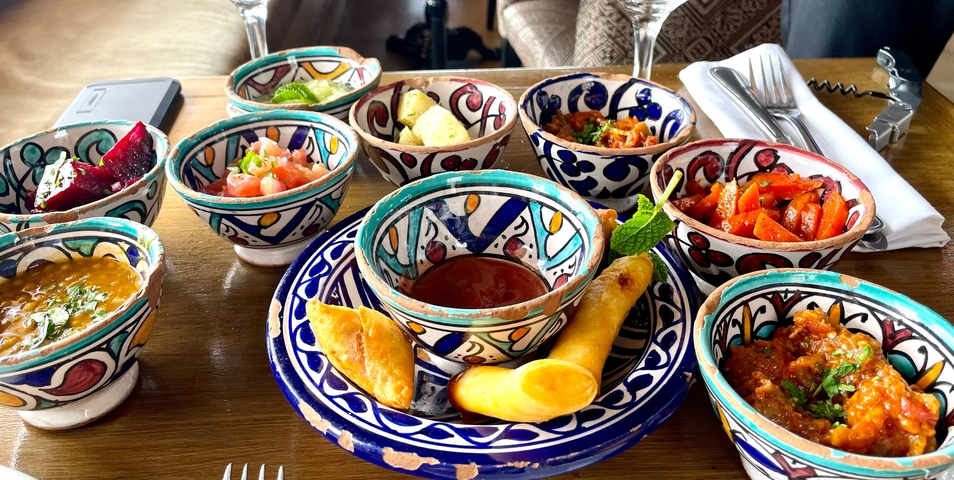       Colorful Moroccan dishes and appetizers on a wooden table.
  