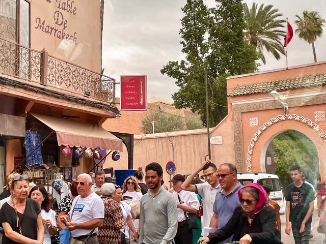       Crowded street scene with Moroccan architecture and signs.
  