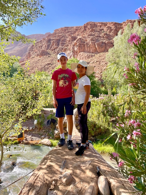       Two people posing in a lush garden setting with flowers.
  