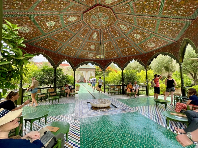       Ornate Moroccan pavilion with people relaxing inside.
  