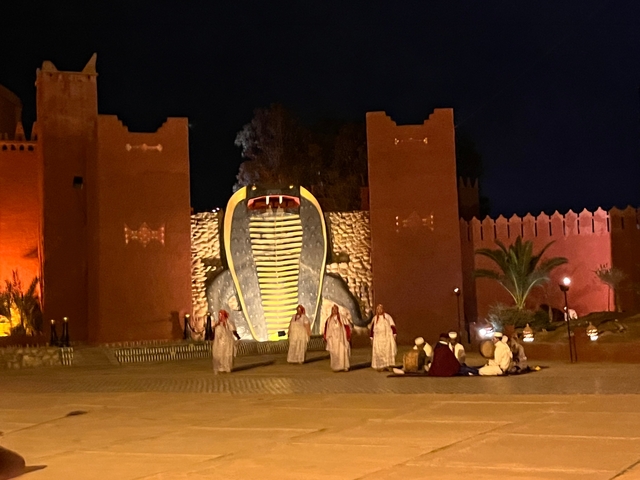 Traditional Moroccan performance with people in cultural attire at night.