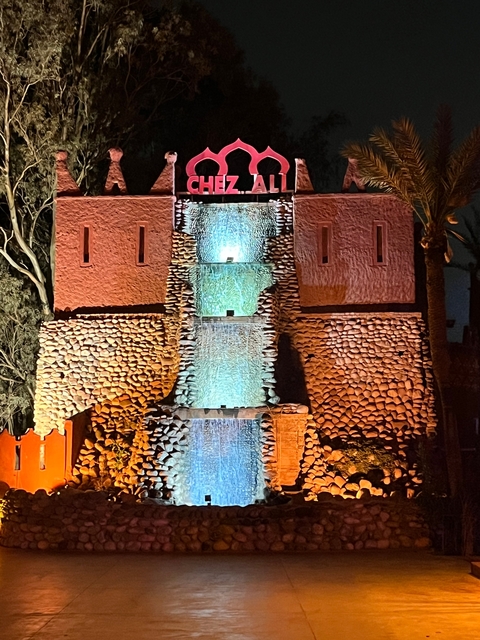 Lit waterfall feature in a cultural setting at night.