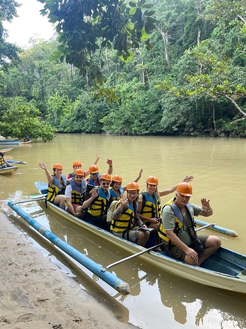       Group of people wearing life jackets on a boat in a river.
  