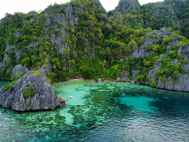 Aerial view of a tropical lagoon with turquoise waters and lush cliffs.