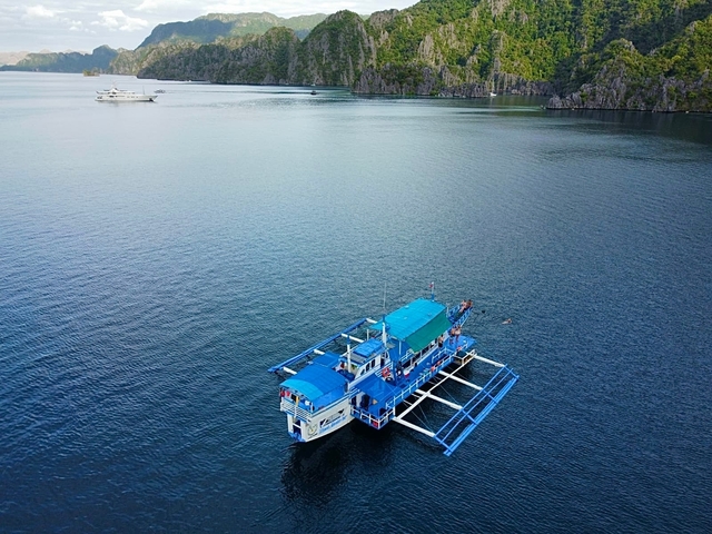 Boat on open water with distant cliffs in the background.