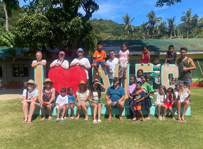       Group of people with children posing in front of a love sign.
  