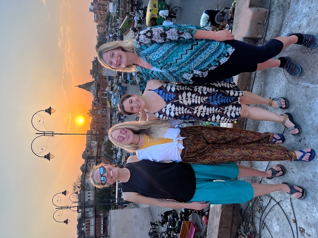       Four women posing on a rooftop with a sunset background.
  