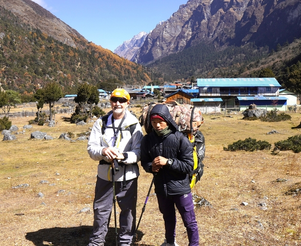       Two hikers in a mountainous village with colorful buildings.
  