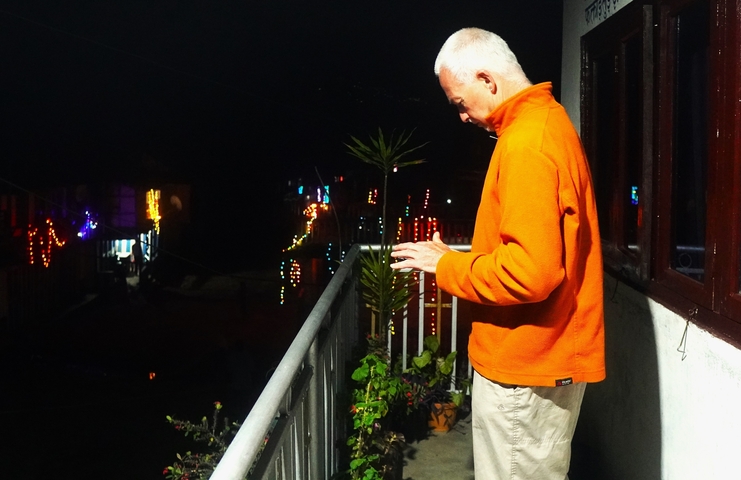       Person standing on a balcony decorated with lights.
  