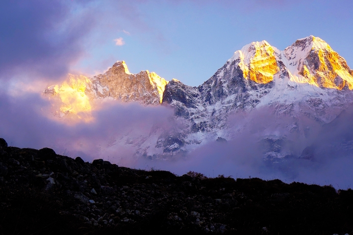       Sunlit mountain peaks partially covered by clouds.
  