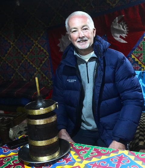       Person sitting inside a cozy tent with a traditional stove.
  