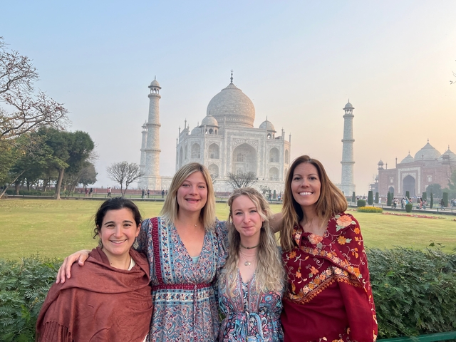       Group of four people posing in front of the Taj Mahal.
  