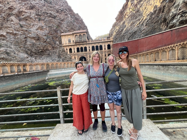       Group of four people posing in front of a historic site.
  