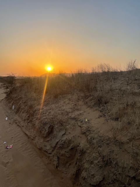       Sunset over a rural landscape with dry vegetation.
  