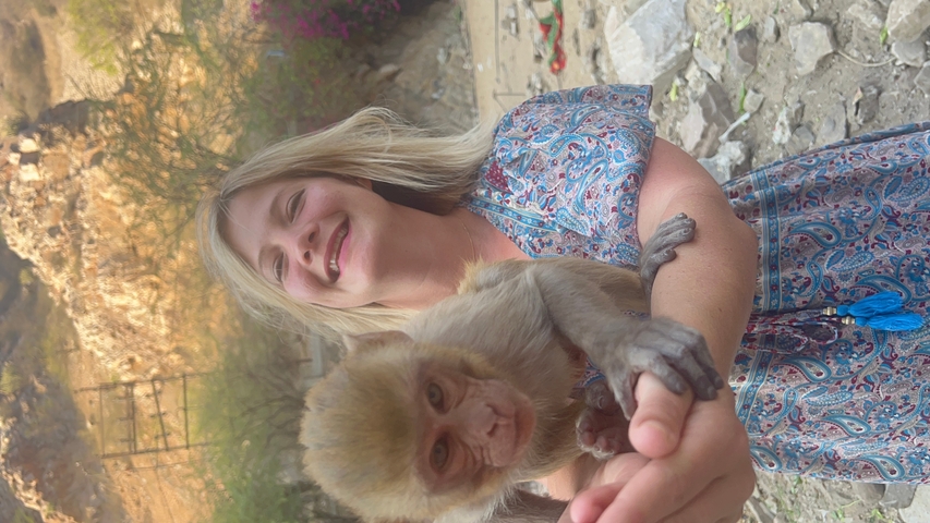       A person holding a small monkey in a rocky environment.
  