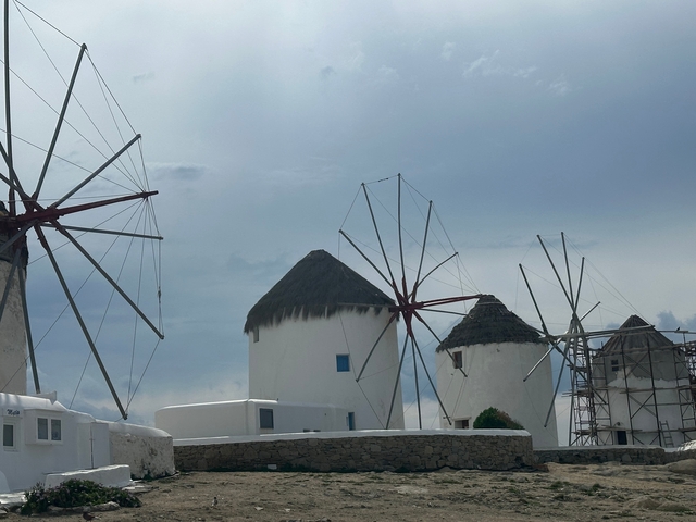 Group of traditional windmills under a cloudy sky.