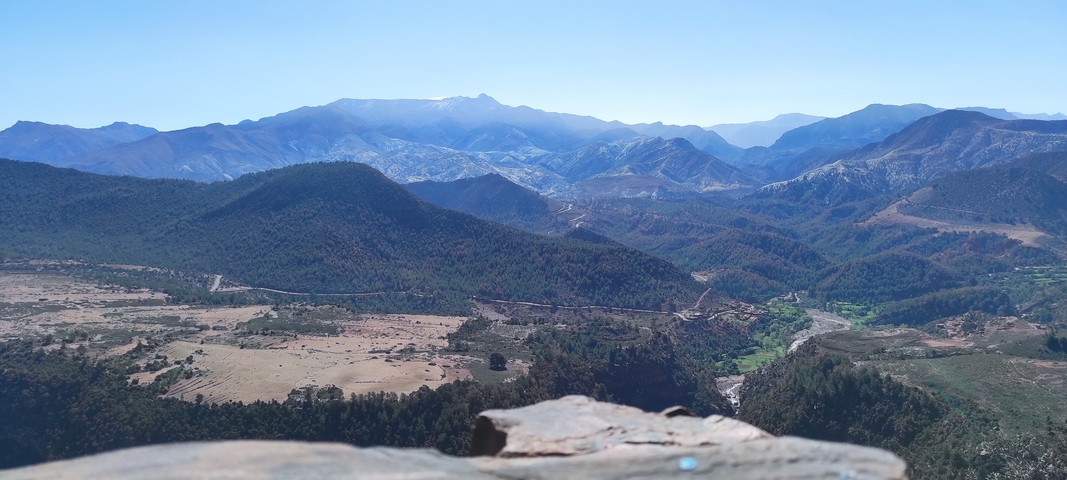 Panoramic view of mountain range with valley and rivers.