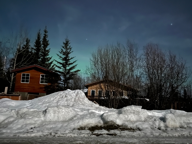 Snow-covered houses and trees under a clear sky.