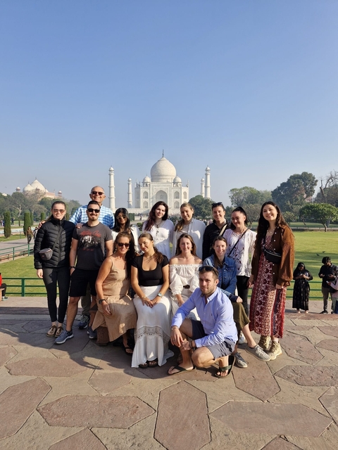       Group of people posing in front of the Taj Mahal.
  