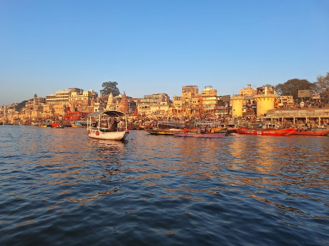       Boats on the Ganges River and colorful buildings.
  
