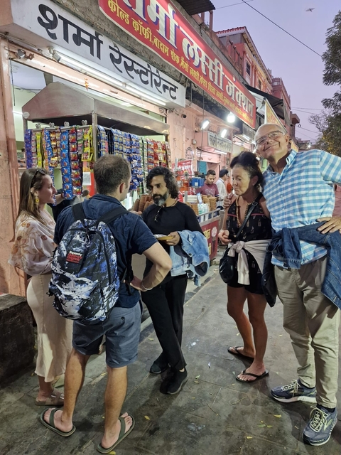       People standing in a street market having a conversation.
  
