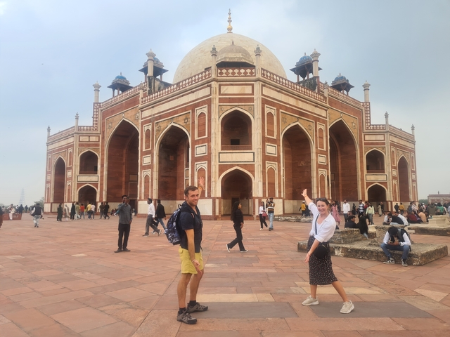       People posing in front of a large historical building.
  