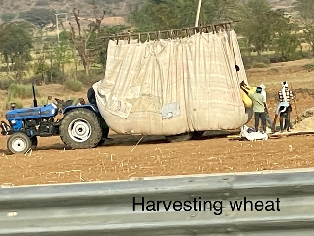       Workers with a tractor and large grain bags in a field.
  