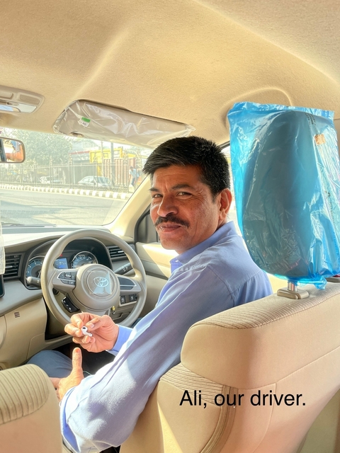       Man driving a car, looking at the camera.
  