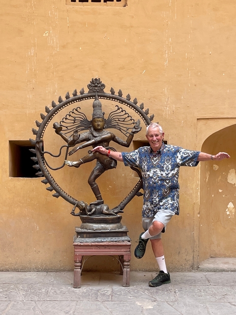 Man posing next to a Nataraja statue.
