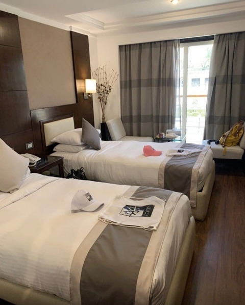 Hotel room with two beds and a balcony view.