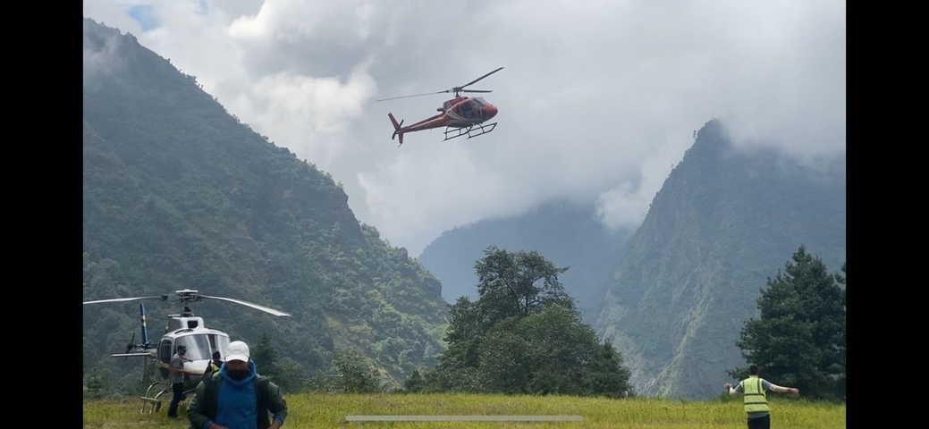 Helicopter flying over mountainous landscape with people below.