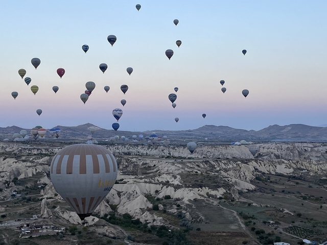 Hot air balloons flying over a rocky landscape at sunrise.