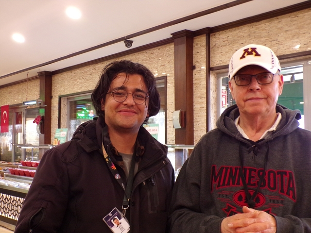       Two men posing inside a restaurant with Turkish flags.
  