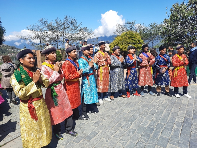       Group of people in traditional colorful attire performing an outdoor activity.
  