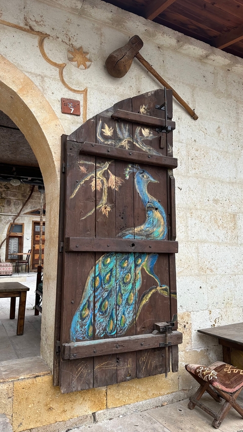 A wooden door painted with a colorful peacock design.