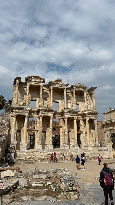 Ancient ruins with intricate carvings under a cloudy sky.