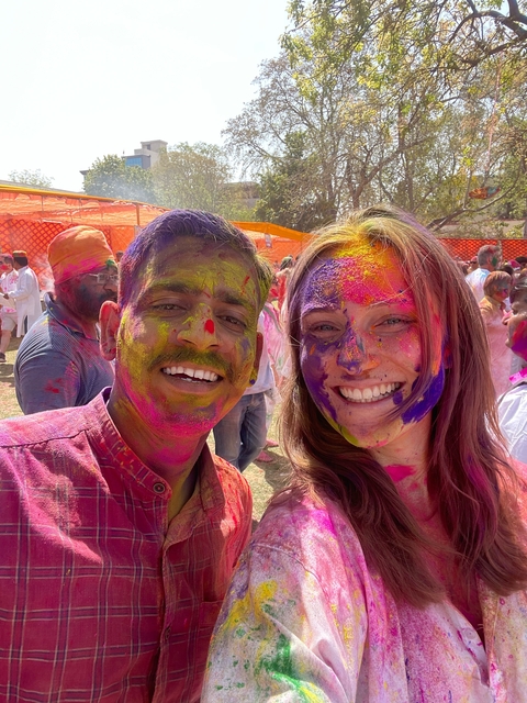       Two people smiling with Holi colors on their faces.
  