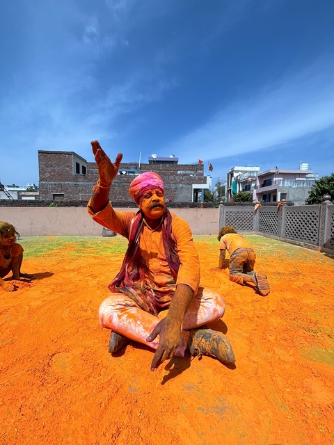       Man celebrating Holi with orange-colored powder.
  