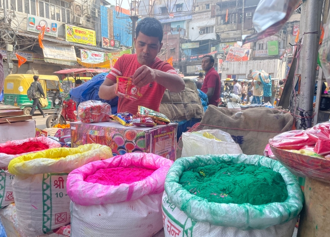       Vendor selling colorful powders on a busy street.
  