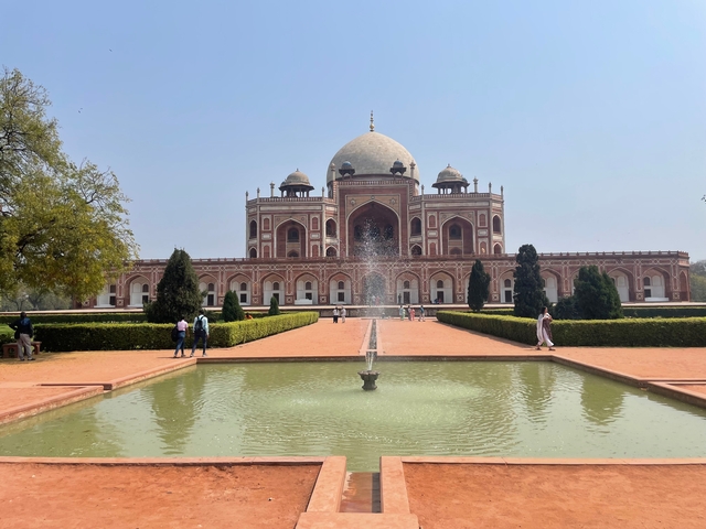       Historical mausoleum with a garden and fountain in front.
  