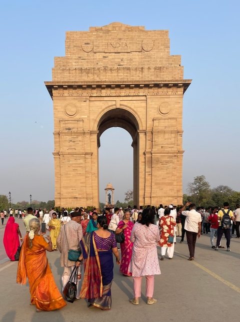       Large stone arch monument with a crowd of people around.
  