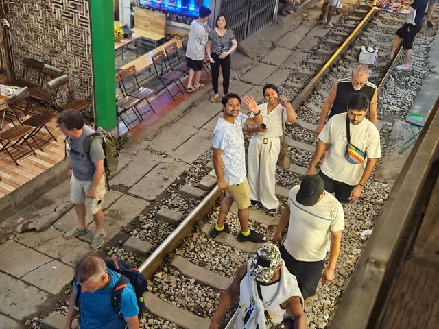       People walking on a railway track at a market.
  