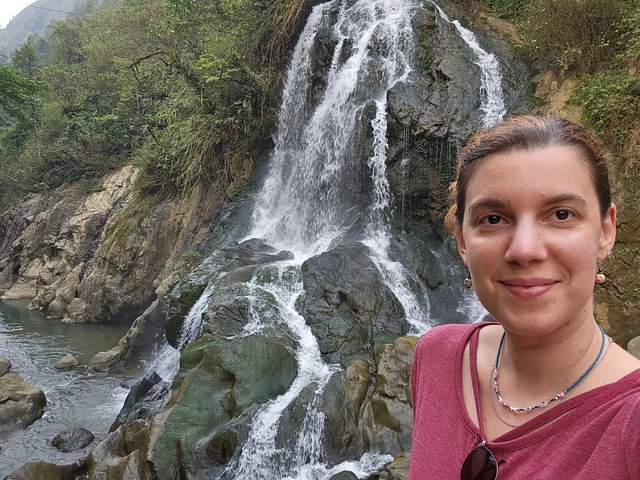       Person in front of a waterfall with rocky surroundings.
  