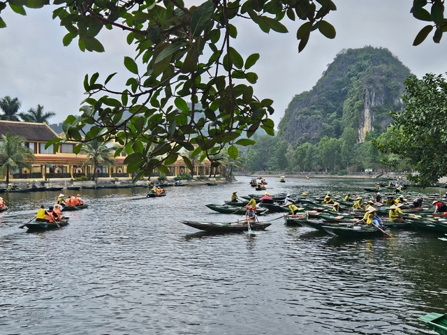       People rowing boats on a river surrounded by lush greenery and mountains.
  
