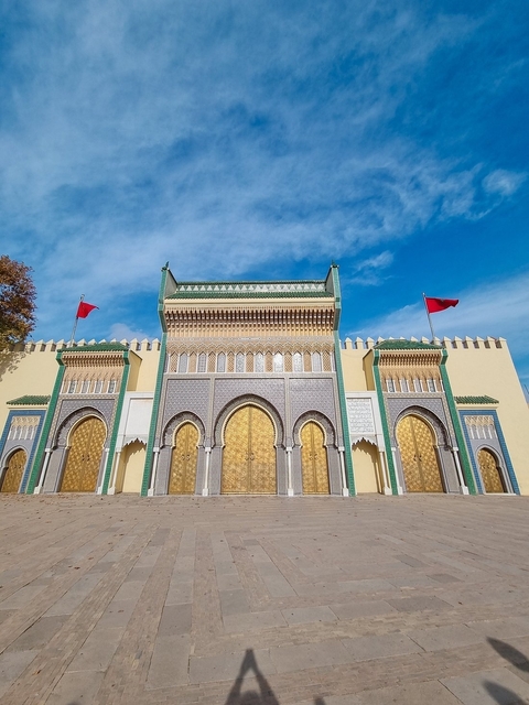 Majestic building with golden doors and flags.